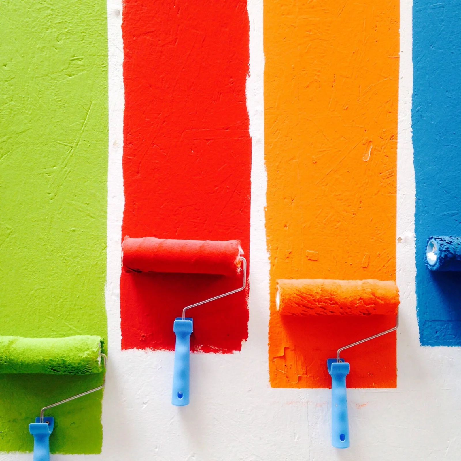 Colorful paint rollers showing green, red, orange and blue paint choices